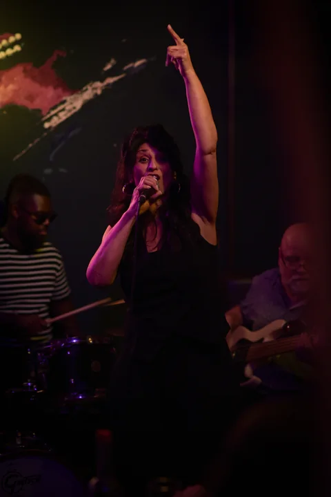 Sängerin mit erhobenem Arm auf der Bühne, Band im Hintergrund