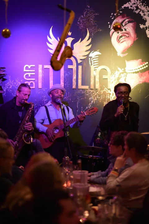 Trio auf der Bühne der Bar Italia, Hochformat, Publikum im Vordergrund