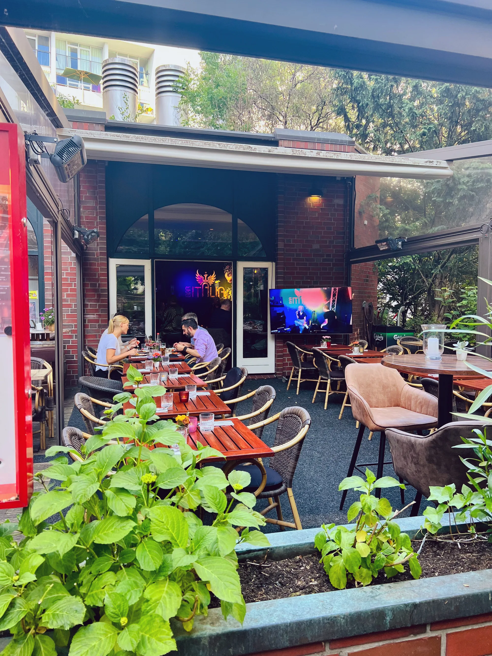Terrasse im Innenhof mit Bepflanzung und Gästen an den Tischen